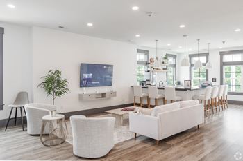 Clubhouse at Wynfield apartments with white couches and chairs and a kitchen area with a television